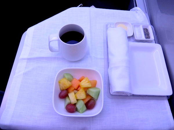 Fresh fruit salad and coffee onboard Air New Zealand business class.